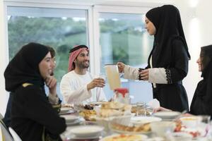 eid Mubarak Muslim Familie haben iftar Abendessen Trinken Wasser zu brechen Fest. Essen traditionell Essen während Ramadan schlemmen Monat beim heim. das islamisch halal Essen und Trinken beim modern Western isla foto