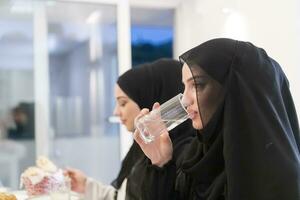 eid Mubarak Muslim Familie haben iftar Abendessen Trinken Wasser zu brechen Fest. Essen traditionell Essen während Ramadan schlemmen Monat beim heim. das islamisch halal Essen und Trinken beim modern Western isla foto