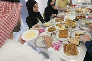 eid Mubarak Muslim Familie haben iftar Abendessen Trinken Wasser zu brechen Fest. Essen traditionell Essen während Ramadan schlemmen Monat beim heim. das islamisch halal Essen und Trinken beim modern Western isla foto