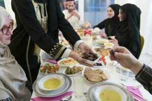 modern multiethnisch Muslim Familie Teilen ein Schüssel von Termine während genießen iftar Abendessen zusammen während ein Ramadan Fest beim Zuhause foto