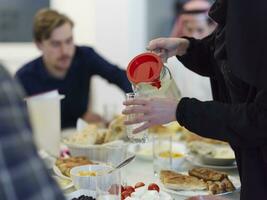 eid Mubarak Muslim Familie haben iftar Abendessen Trinken Wasser zu brechen Fest. Essen traditionell Essen während Ramadan schlemmen Monat beim heim. das islamisch halal Essen und Trinken beim modern Western isla foto