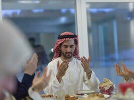 muslimische familie, die iftar dua macht, um während des ramadan das fasten zu brechen. foto