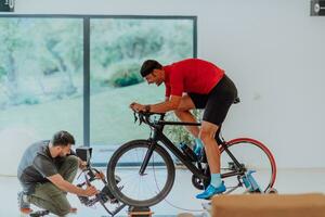 ein Kameramann filmen ein Athlet Reiten ein Triathlon Fahrrad auf ein Simulation Maschine im ein modern Leben Zimmer. Ausbildung im Pandemie Bedingungen. foto