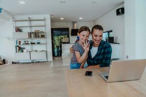 Mutter mit ihr Tochter reden auf Laptop mit Familie und freunde während Sitzung im modern Leben Zimmer von groß Haus foto