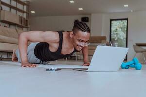 Ausbildung beim heim. sportlich Mann tun Ausbildung während Aufpassen online Lernprogramm auf Laptop, ausüben im Leben Zimmer, kostenlos Raum foto
