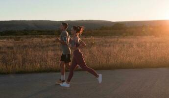 gesund jung Paar Joggen im das Stadt Straßen im das früh Morgen mit ein schön Sonnenaufgang im das Hintergrund. foto