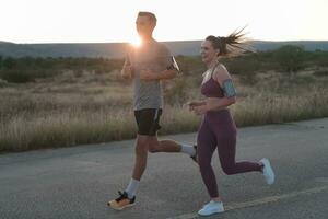 gesund jung Paar Joggen im das Stadt Straßen im das früh Morgen mit ein schön Sonnenaufgang im das Hintergrund. foto