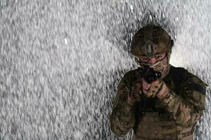 Heer Soldat im Kampf Uniformen mit ein Angriff Gewehr, Teller Träger und Kampf Helm gehen auf ein gefährlich Mission auf ein regnerisch Nacht. foto