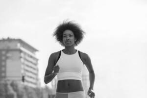 Porträt einer sportlichen jungen afroamerikanischen Frau, die im Freien läuft foto