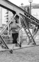 Frau, die am sonnigen Morgen über die Brücke joggt foto