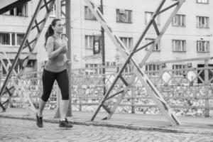 Frau, die am sonnigen Morgen über die Brücke joggt foto