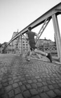 Mann, der am sonnigen Morgen über die Brücke joggt foto