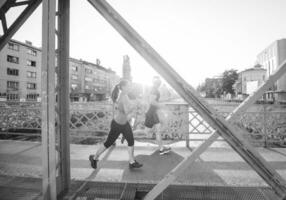 junges Paar joggt über die Brücke in der Stadt foto