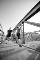 junges Paar joggt über die Brücke in der Stadt foto