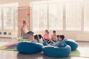 lesen Zeit im elementar Schule oder Kindergarten, Lehrer lesen ein Buch zu Kinder im elementar Schule oder Kindergarten. selektiv Fokus foto