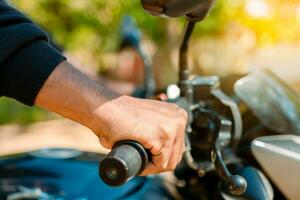 Hände von Mann auf das Motorrad Lenker. Motorrad Beschleunigen Konzept, Hände von ein Motorradfahrer auf das Lenker. schließen oben von das Hände auf das Lenker von ein Motorrad foto