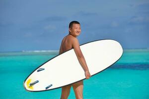 Mann mit Surfbrett am Strand foto