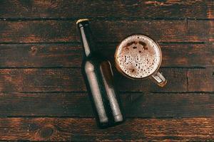 Draufsichtfoto von Flaschenbier und Bierglas über Holzhintergrund foto