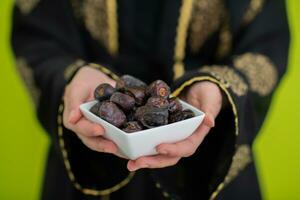 modern Muslim Frau halten ein Teller voll von Süss Termine auf iftar Zeit im Ramadan kareem islamisch gesund Essen Konzept UFO Grün Hintergrund foto