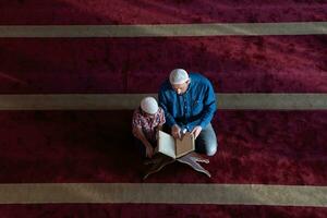 muslimischer gebetsvater und sohn in der moschee beten und lesen holly book quran zusammen islamisches bildungskonzept foto