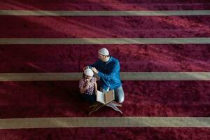 muslimischer gebetsvater und sohn in der moschee beten und lesen holly book quran zusammen islamisches bildungskonzept foto