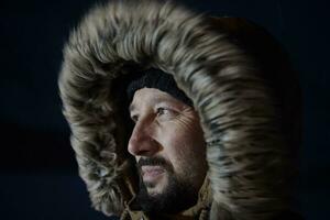 Mann im Winter bei stürmischem Wetter in der Nacht mit warmer Pelzjacke foto