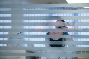 Junge Geschäftsfrau, die durch eine transparente Wand schaut foto