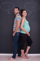 Schwangeres Paar, das auf einer schwarzen Tafel schreibt foto