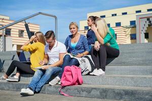 Studenten sitzen draußen auf Stufen foto