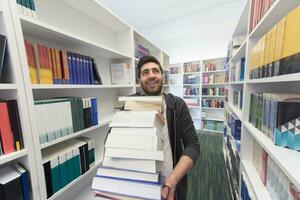 schüler, der viele bücher in der schulbibliothek hält foto