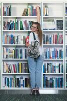 Studentin, die ein Buch zum Lesen in der Bibliothek auswählt foto