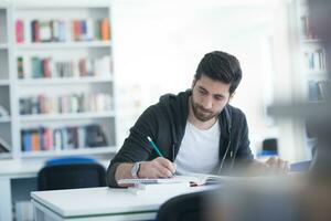 Schüler in der Schulbibliothek mit Laptop für die Recherche foto