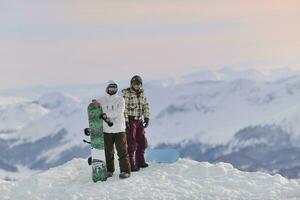 Snowboarderpaar auf dem Gipfel des Berges foto