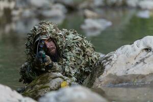 ein Militär- Mann oder Airsoft Spieler im ein tarnen passen schleichen das Fluss und Ziele von ein Scharfschütze Gewehr zu das Seite oder zu Ziel. foto