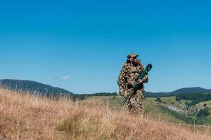 Heer Soldat halten ein Scharfschütze Gewehr mit Umfang und Gehen im das Wald. Krieg, Armee, Technologie und Menschen Konzept. foto