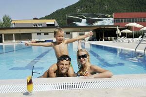 glückliche junge familie hat spaß am schwimmbad foto