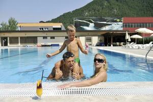 glückliche junge familie hat spaß am schwimmbad foto