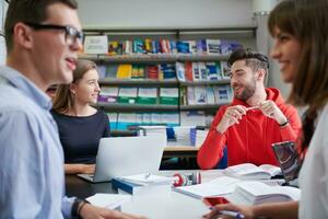 studentengruppe, die gemeinsam an einem schulprojekt auf einem tablet-computer an einer modernen universität arbeitet foto