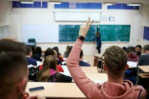 Der Student hebt die Hände und stellt im College eine Frage foto