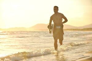 Porträt eines jungen Kitsurf-Mannes am Strand bei Sonnenuntergang foto
