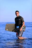 Porträt eines jungen Kitsurf-Mannes am Strand bei Sonnenuntergang foto