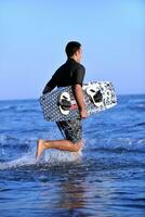 Porträt eines jungen Kitsurf-Mannes am Strand bei Sonnenuntergang foto