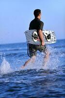 Porträt eines jungen Kitsurf-Mannes am Strand bei Sonnenuntergang foto