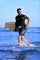 Porträt eines jungen Kitsurf-Mannes am Strand bei Sonnenuntergang foto