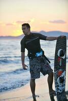 Porträt eines jungen Kitsurf-Mannes am Strand bei Sonnenuntergang foto