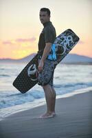 Porträt eines jungen Kitsurf-Mannes am Strand bei Sonnenuntergang foto