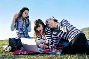 Gruppe von Teenagern, die im Freien am Laptop arbeiten foto