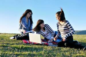 Gruppe von Teenagern, die im Freien am Laptop arbeiten foto