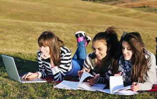 Gruppe von Teenagern, die im Freien am Laptop arbeiten foto