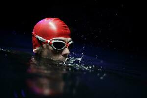 authentischer triathlet-schwimmer, der nachts während des harten trainings eine pause macht foto
